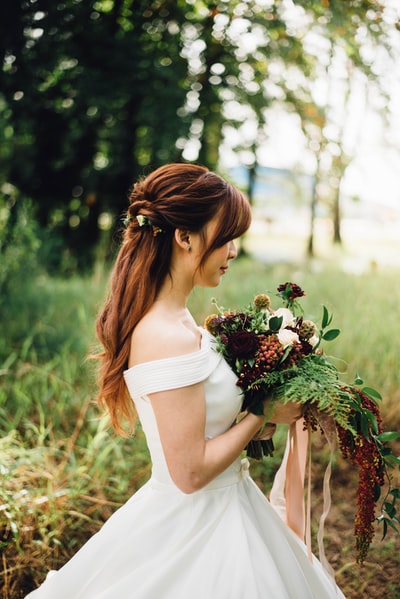 女人穿着白色了肩膀婚纱穿着白色有花瓣的花
